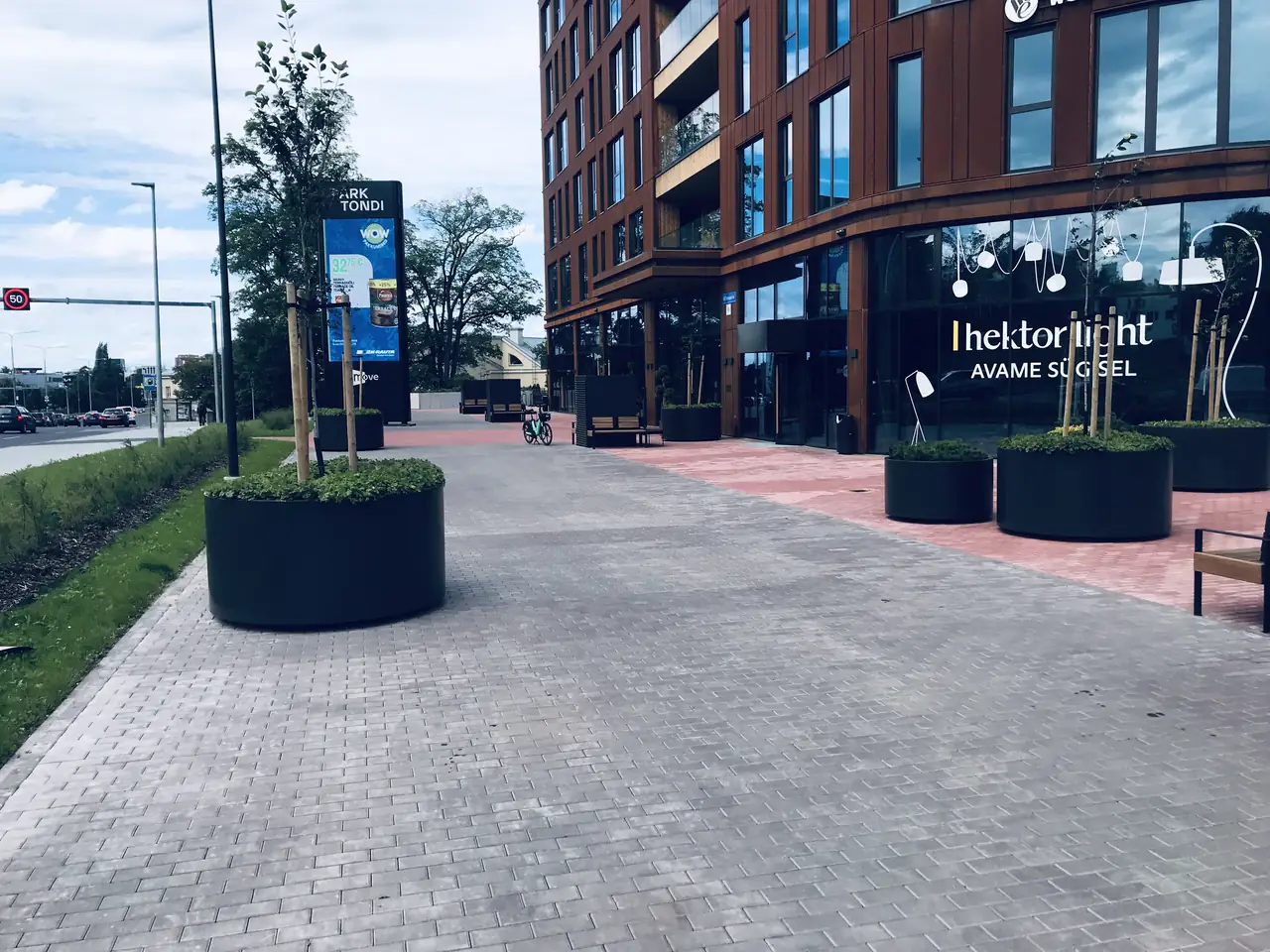 Ärihoone ees heleda ja punase tänavakiviga sillutatud plats istutuskastide ja pinkidega