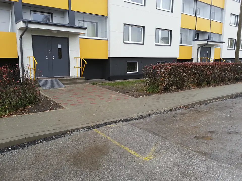 Korterelamu sissepääsu ees uus sillutatud kõnnitee punaste kividega ja äärekivid sõidutee ääres