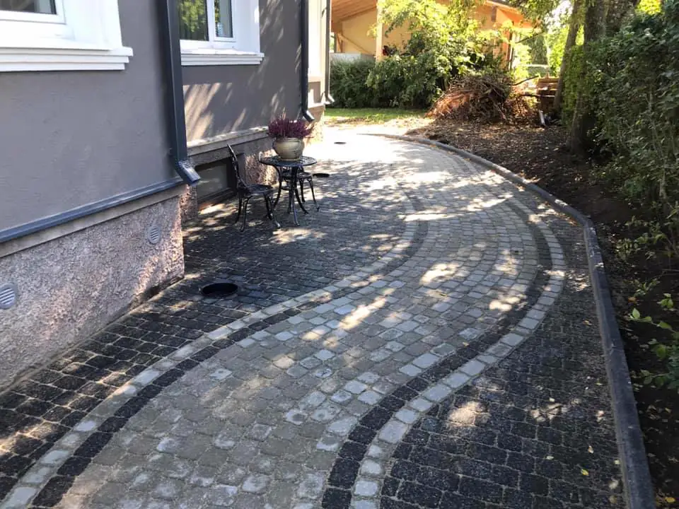 Hallidest ja mustadest munakividest kaarjas kõnnitee maja ääres